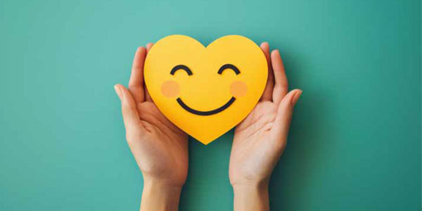 Manos sosteniendo una carita feliz con corazón